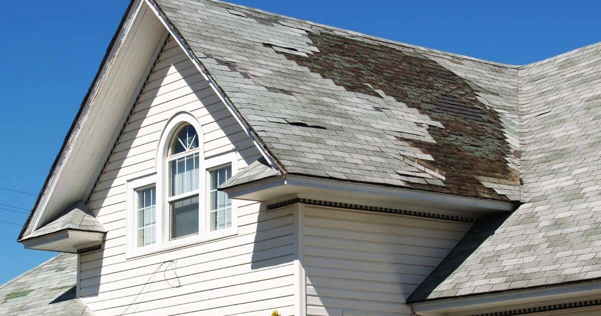 Old roof on residential house with mold and broken shingles